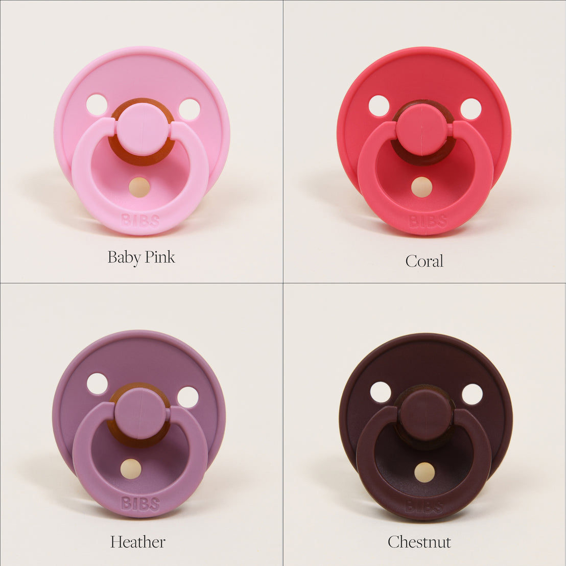 Four Bibs Pacifiers in different colors labeled individually: baby pink, coral, heather, and chestnut, each displayed against a solid, light background. These are natural rubber baby pacifiers designed in Denmark.
