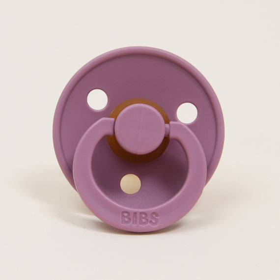 A Bibs Pacifier in Heather, with a round shield and two air holes, featuring a handle and rubber nipple, set against a plain white background.