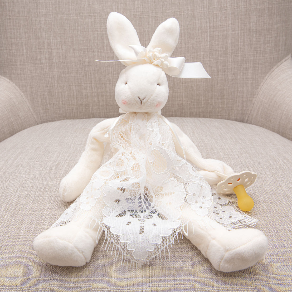 Close up photo of the bunny buddy pacifier holder. Bunny is wearing lace from the Victoria Christening Gown Collection.