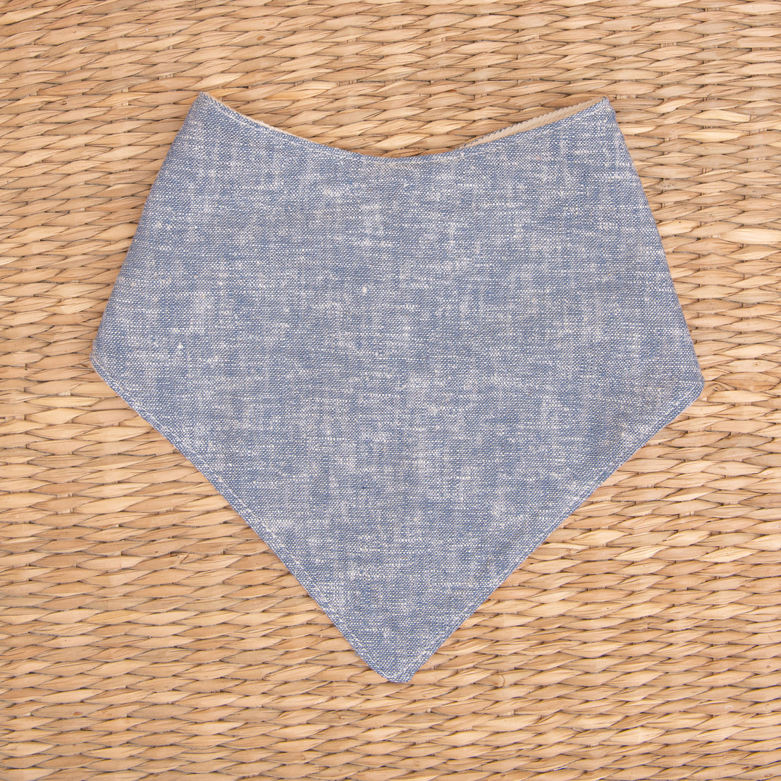 Flat lay photo of the indigo colored Silas Bandana Bib in a woven basket