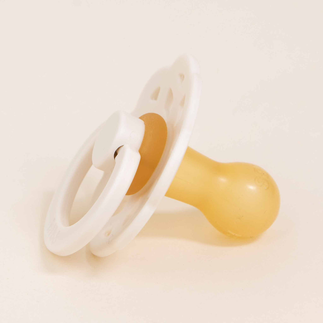A Bibs Lace Pacifier in Ivory with a yellow nipple and white handle, designed in Denmark, set against a soft beige background.