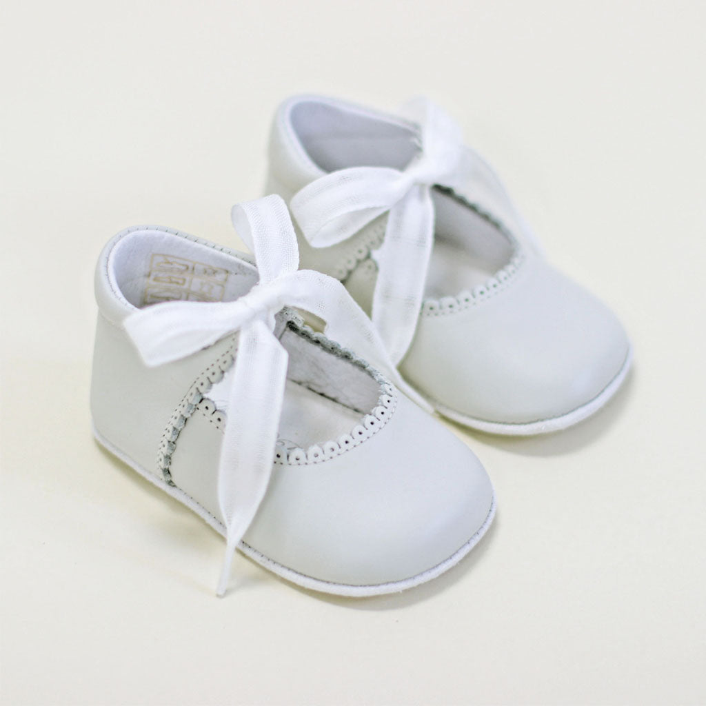 A pair of Ivory Tie Mary Janes with ribbon laces on a light beige background. The shoes feature delicate stitching and soft, flexible soles.