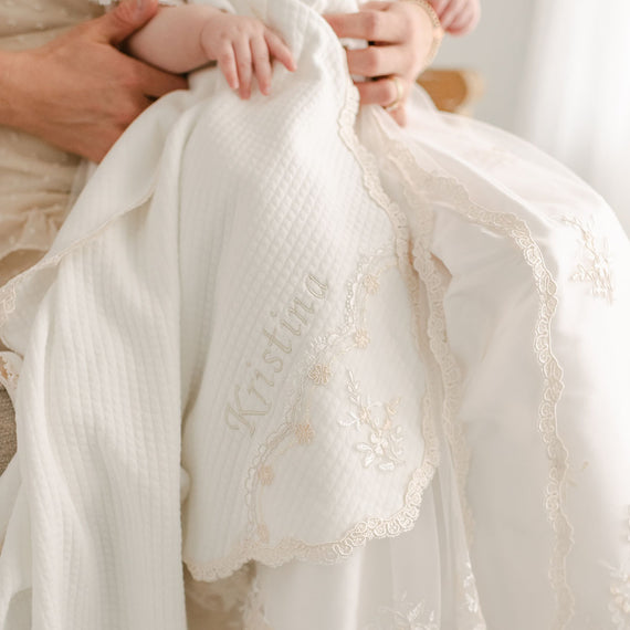 Close-up of a baby wrapped in a Kristina Personalized Blanket, held securely by an adult's hands.