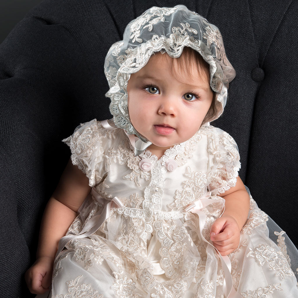 Baby girl wearing lace and silk christening gown, including her Lace baptism bonnet.