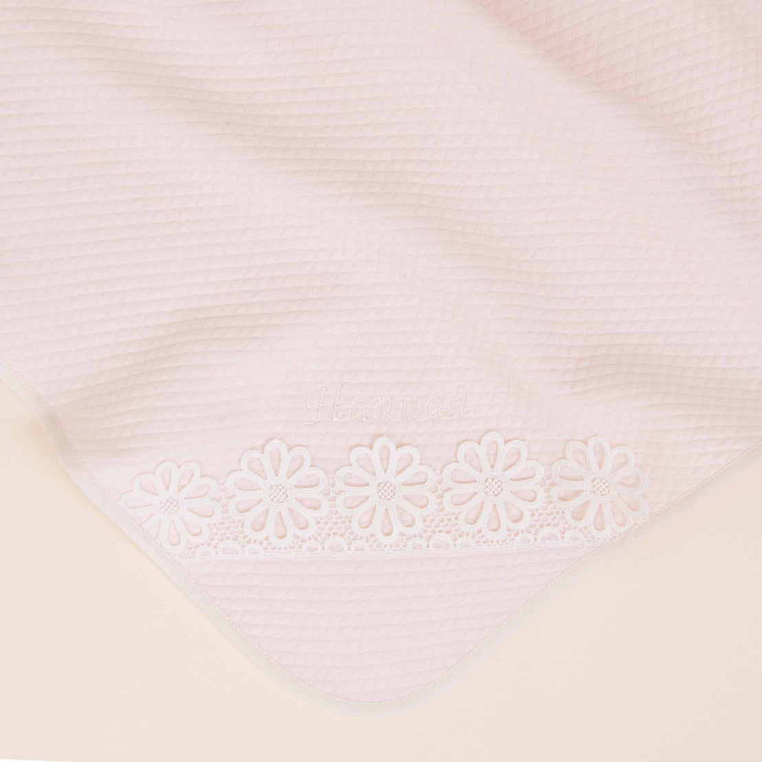 Close-up of a pale pink fabric with a delicate, white lace border featuring a floral pattern, set against a light background, ideal for Baby Beau & Belle's Hannah Personalized Blanket.