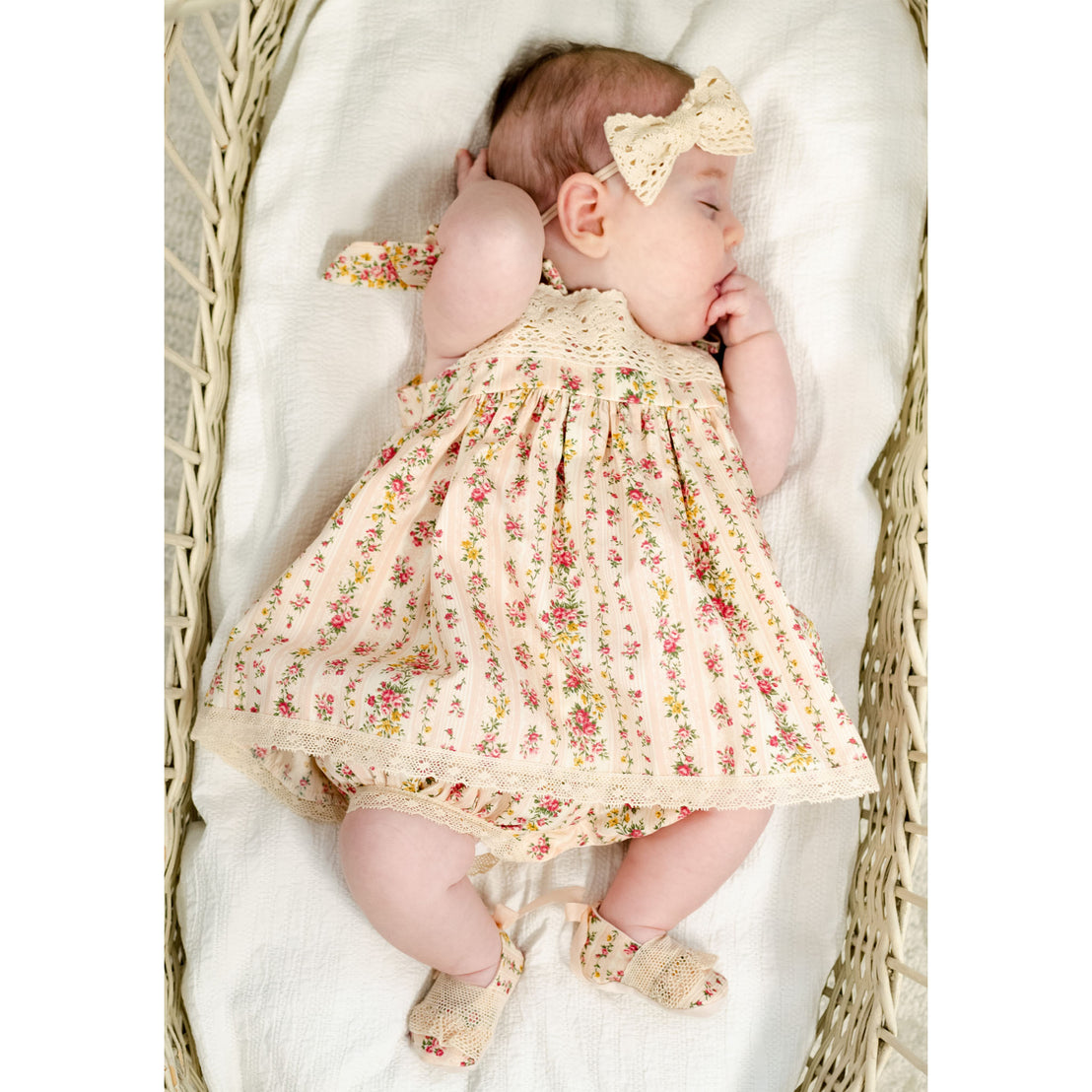 Newborn baby girl wearing the "Blush" Eloise Romper Dress and matching Eloise Bow Headband. 