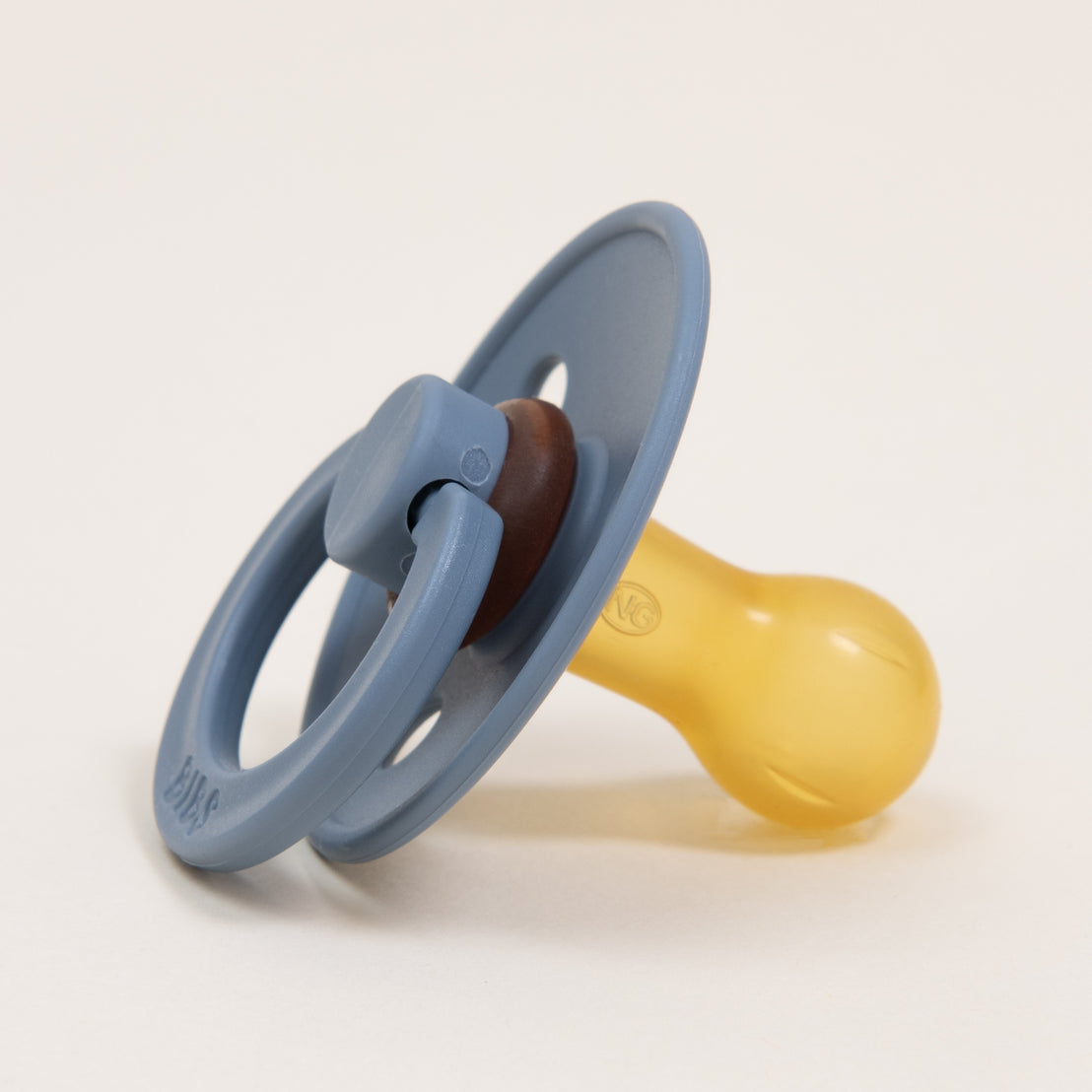 A Bibs Pacifier in Petrol with a blue shield and handle, and a yellow nipple, positioned upright on a white background.