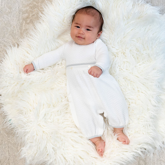 Baby boy laying on rug wearing the Grayson baby boy romper, made of super soft quilted cotton.