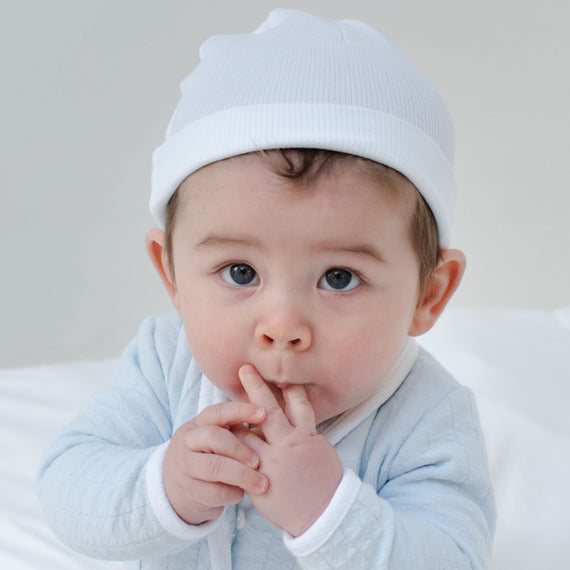 Baby boy wearing the White Ribbed Cotton Beanie made from 100% ribbed textured cotton.