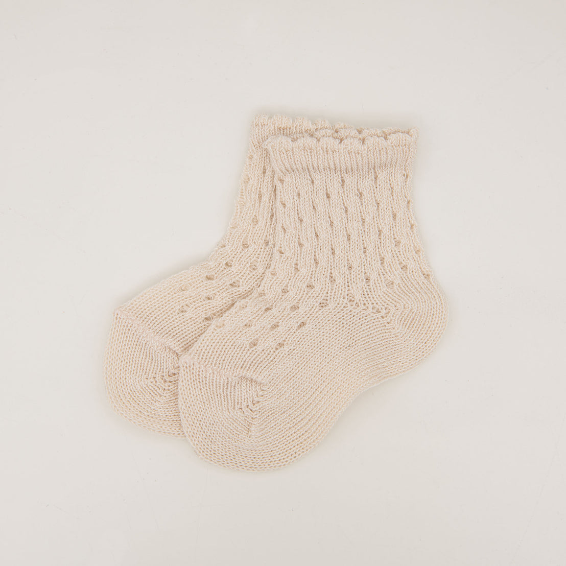 A pair of cozy, beige Scallop Edge Crochet Socks displayed on a plain white background, featuring a ribbed design with delicate patterns near the cuffs.