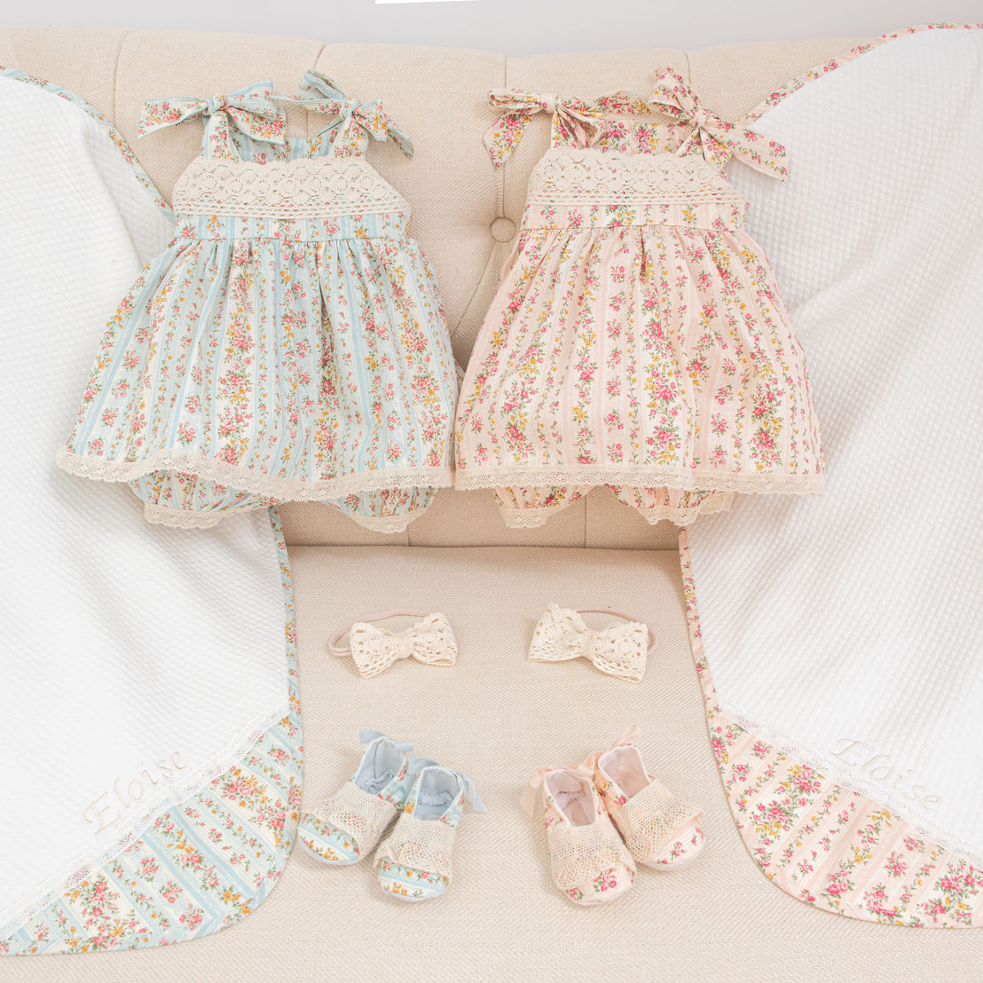Comparison of the "Blush" and "Powder Blue" variant colors of the Eloise Romper Dress, Booties, Bow Headband, and Personalized Blanket.