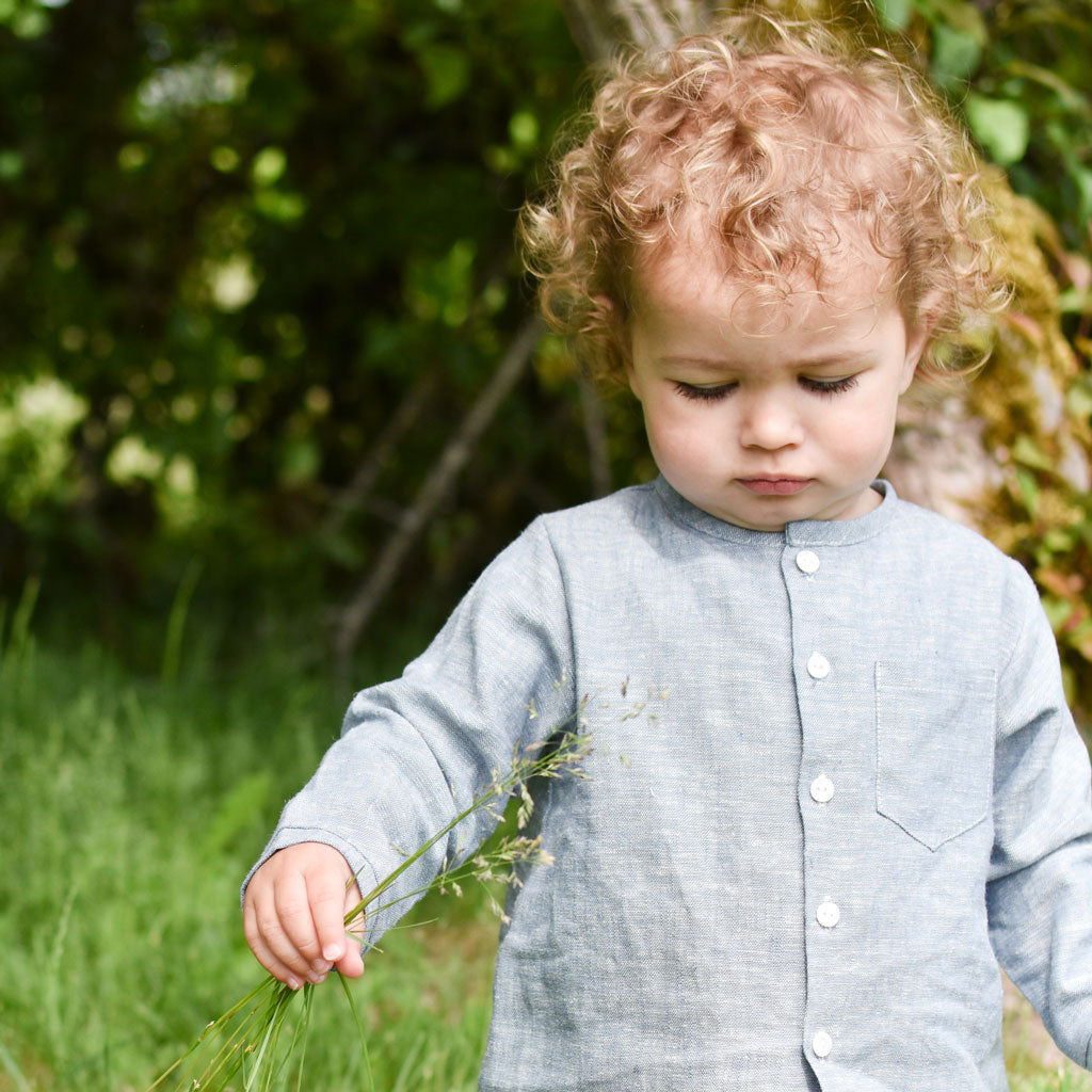 Photo of a baby boy outside in the forest wearing the Silas Linen Shirt in indigo