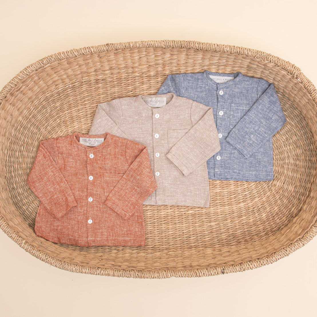 Flat lay photo of all three colors of the Silas Linen Shirt. The collarless shirt is a made from linen in three different colors: indigo, sand, and clay.