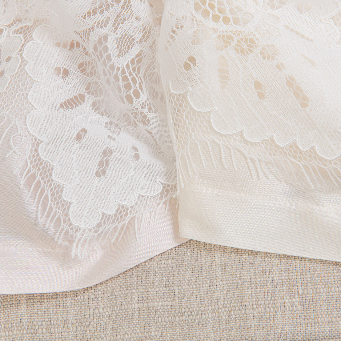Close-up detail shot of the lace details on the Victoria Christening Gown. Two different colors shown - ivory and pink.