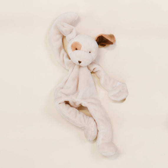 A soft, plush toy rabbit with floppy ears, one ear brown and the other white, on a light beige background. The Baby Beau & Belle Silly Puppy Buddy pacifier holder is lying flat, facing upwards.