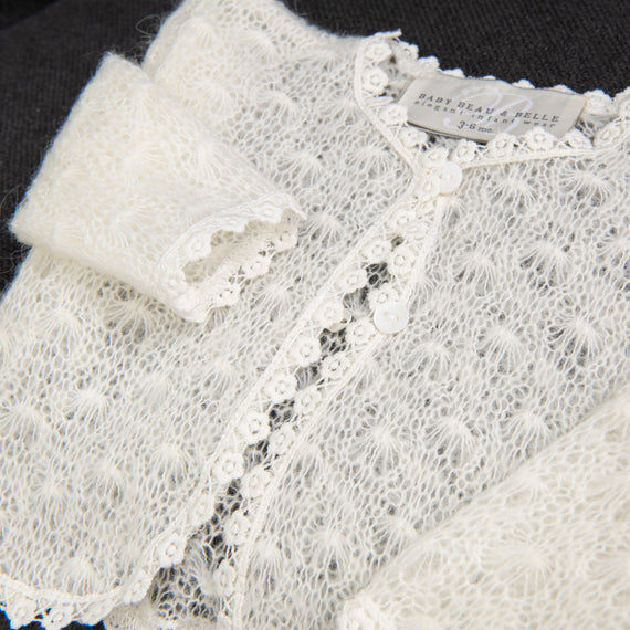 Close-up of a delicate white cotton lace Grace Knit Sweater with pearl button details.