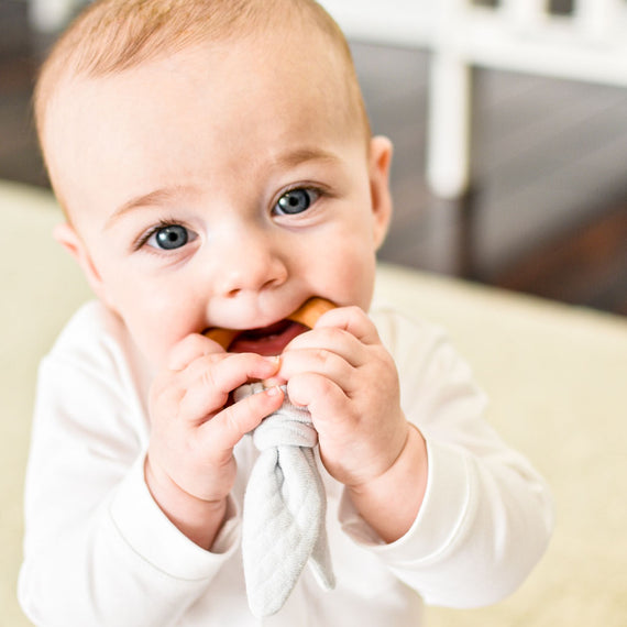 Baby boy with wooden teether ring.