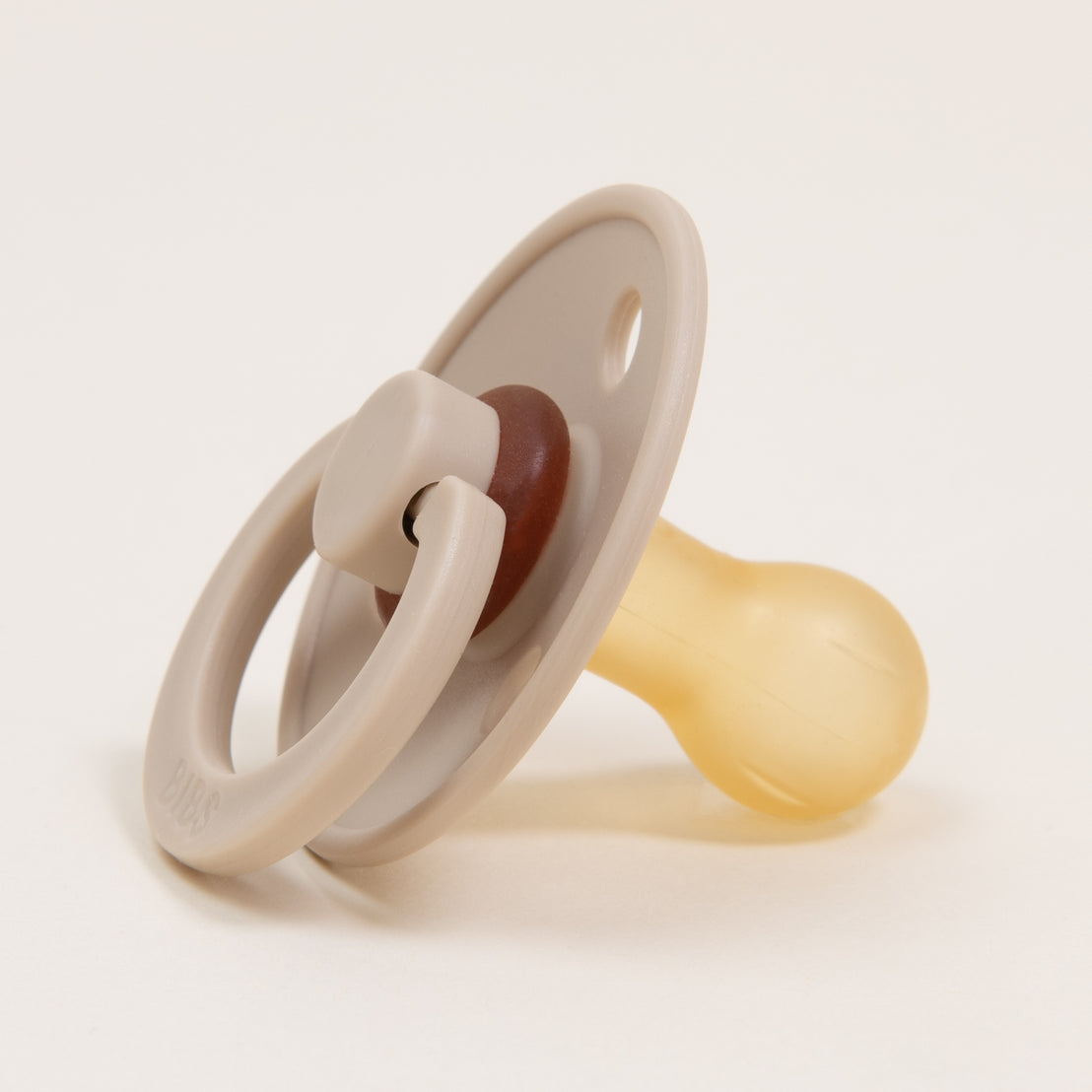 A close-up image of a Bibs Pacifier in "vanilla" on a white background, featuring classic design with three circular holes around the shield.