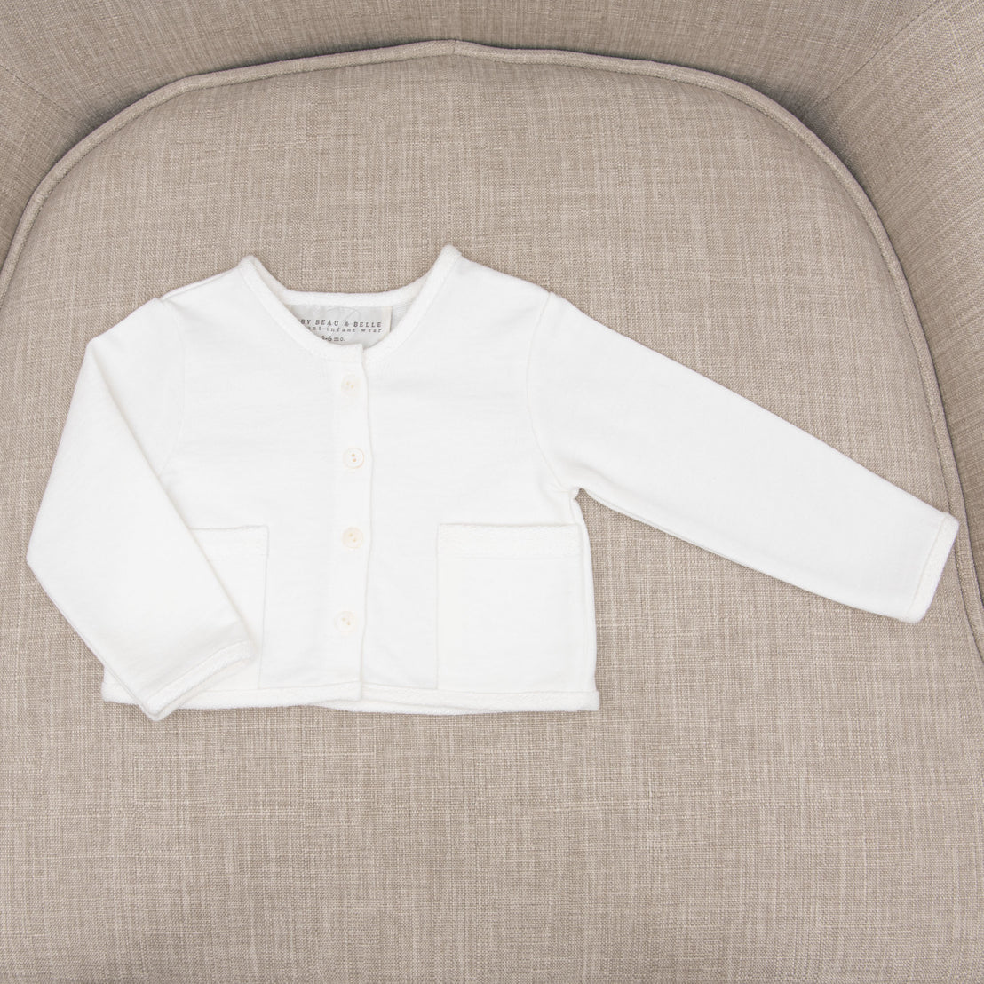 A designer white Ian French Terry Jacket with long sleeves, three buttons, and two front pockets displayed flat on a gray textured background.
