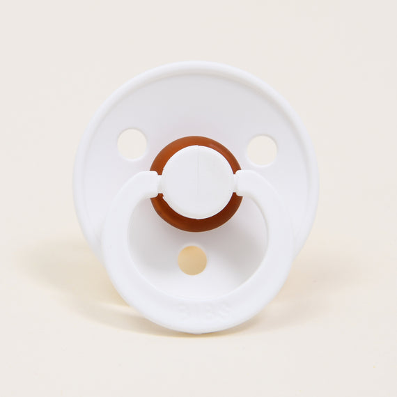 A white and brown Bibs Pacifier 2 Pack isolated on a pale background, featuring air holes and a pull handle, perfect as an upscale baby gift.