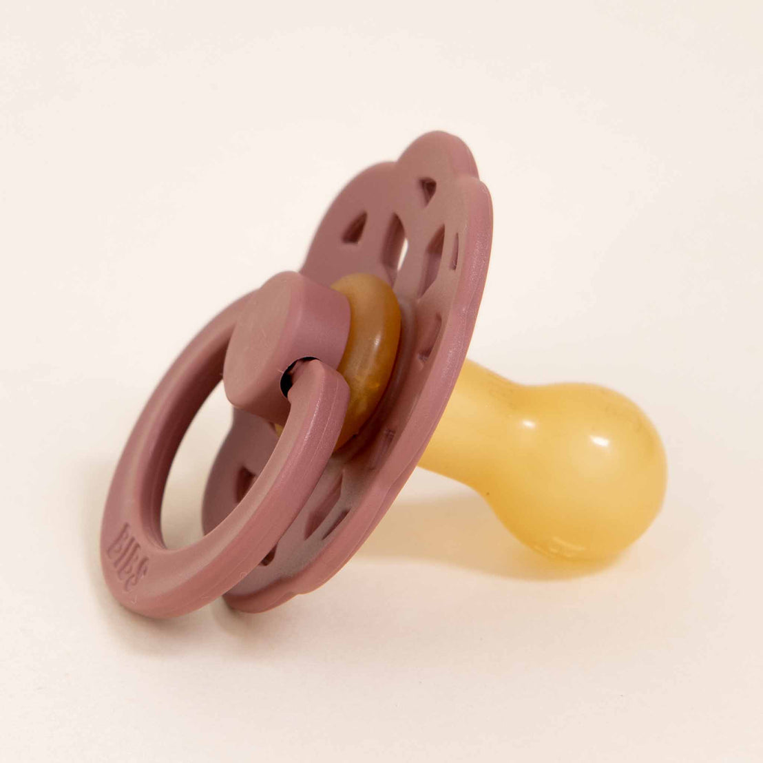 A Bibs Lace Pacifier in Woodchuck with a rubber nipple, featuring a bohemian-inspired design on the shield, set against a light beige background.