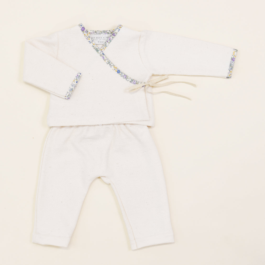 An upscale, Petite Fleur Wrap Top & Pants baby outfit featuring a kimono-style top with floral trim and matching pants, displayed on a plain light background.
