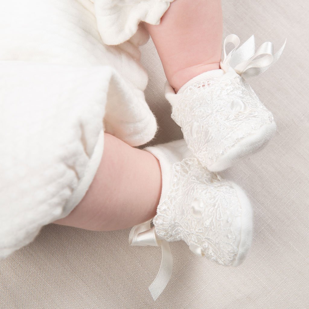 A close-up image of a baby's feet wearing Madeline Quilted Booties, showcasing the upscale, delicate fabric and ribbon detail, perfect for a boutique baby gift.