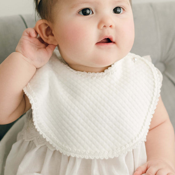 Cute baby girl wearing the Victoria quilted cotton baptism bib.
