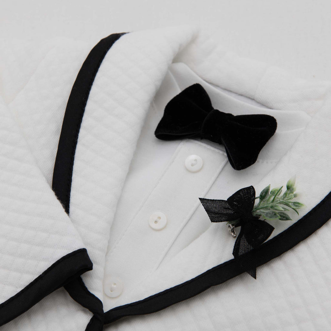 Flat lay photo of the James Bow Tie and Boutonniere on the white James Jacket.
