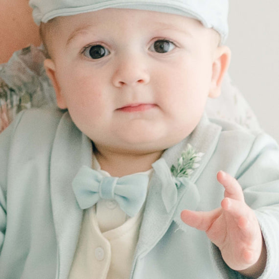 Baby boy wearing the Ezra Powder Blue 4-Piece Suit. Featured in the photo is the Blue Velvet Bow Tie and Boutonniere