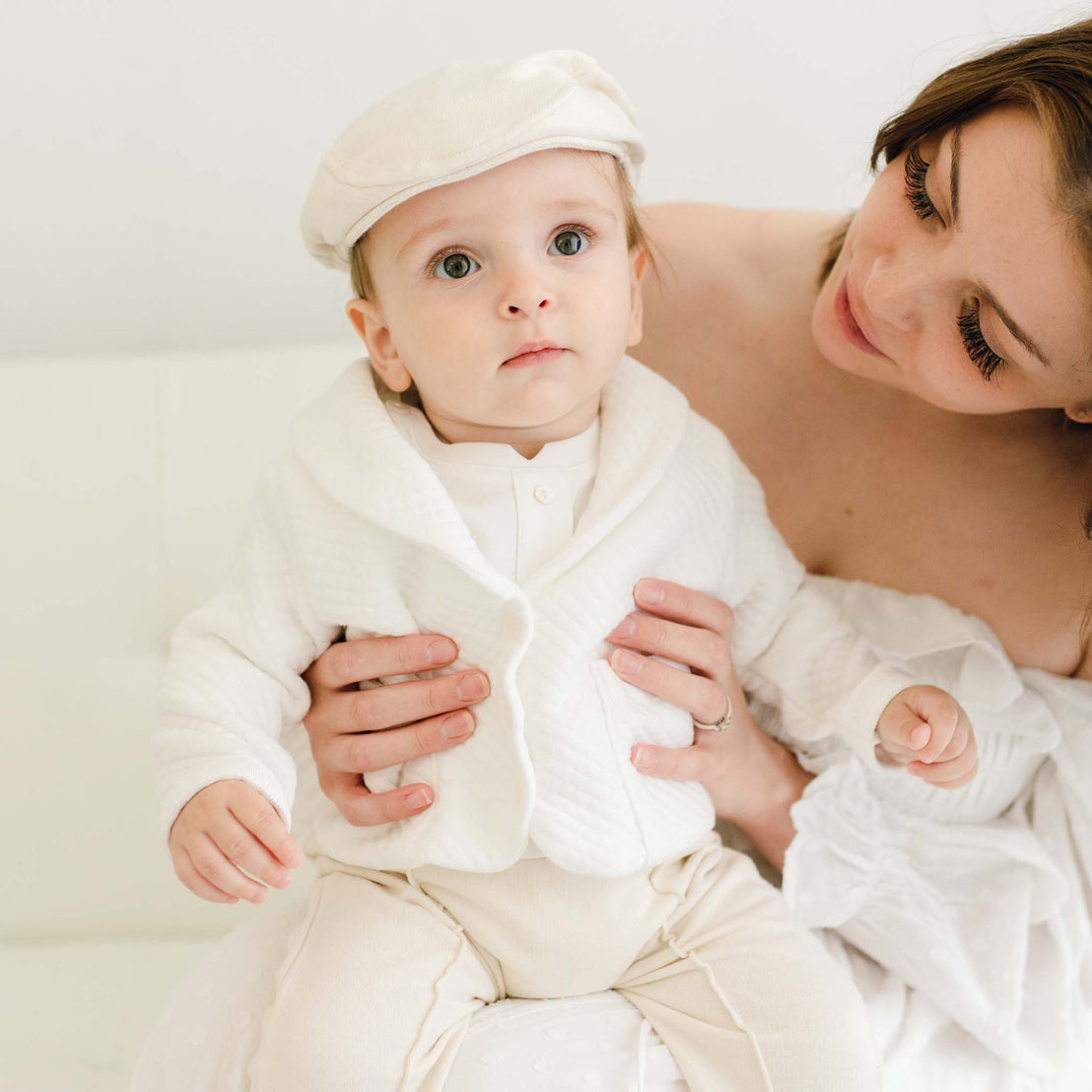 Baby boy sitting on his mother's lap. He is wearing the Braden 3-Piece Suit with the Newsboy Cap