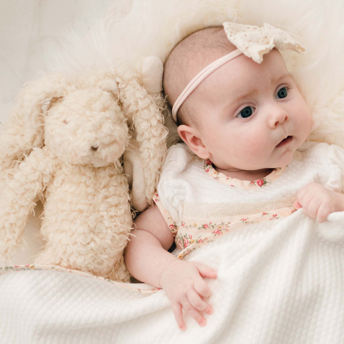 Close up photo of a newborn baby girl with the Eloise Bunny, a super soft stuffed animal bunny with a tan scraggly fur body.