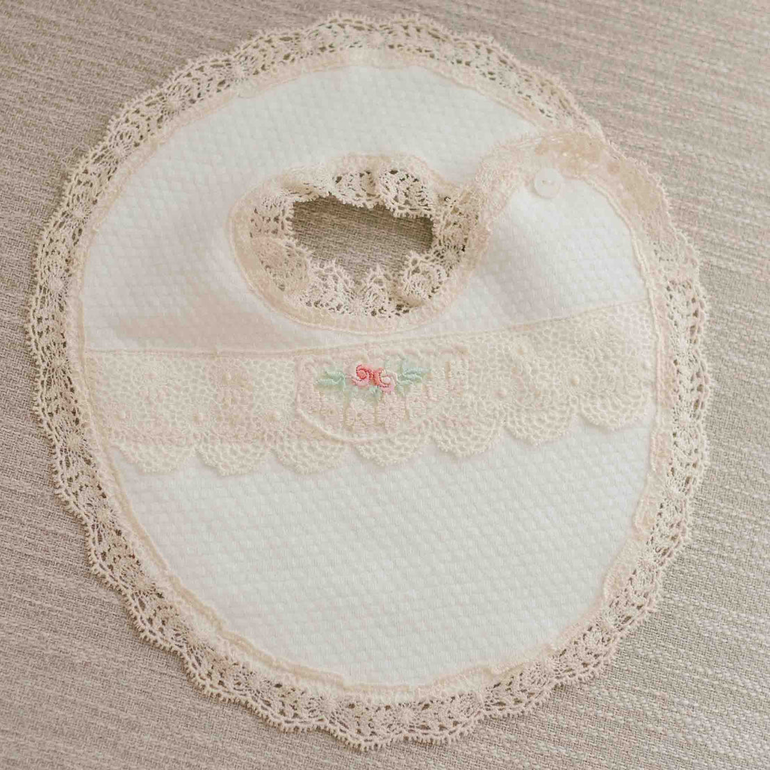 Flat lay of the Chloe Bib. The bib features white quilt with lace embroidery details on the side.