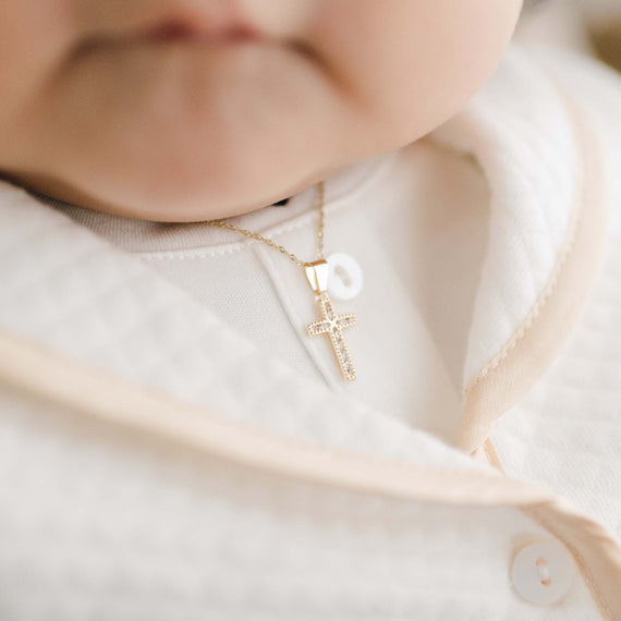 Gold and crystal cross charm necklace on baby