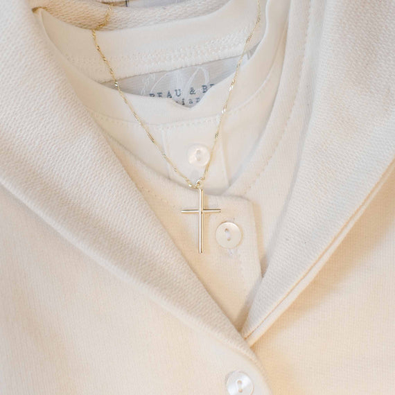 The 14k Gold Cylindrical 'INRI' Cross Charm With Chain is elegantly showcased against a cream-colored, buttoned-down shirt.