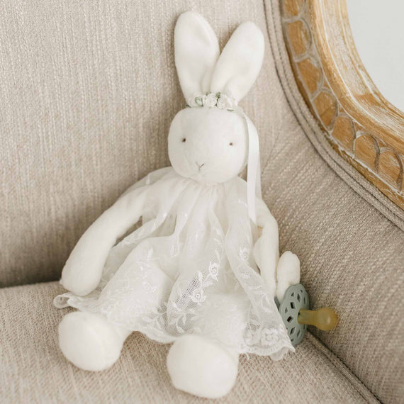 A flat lay photo of the Ella Silly Bunny Buddy dressed in a mini Ella Lace Romper Dress and floral headband.