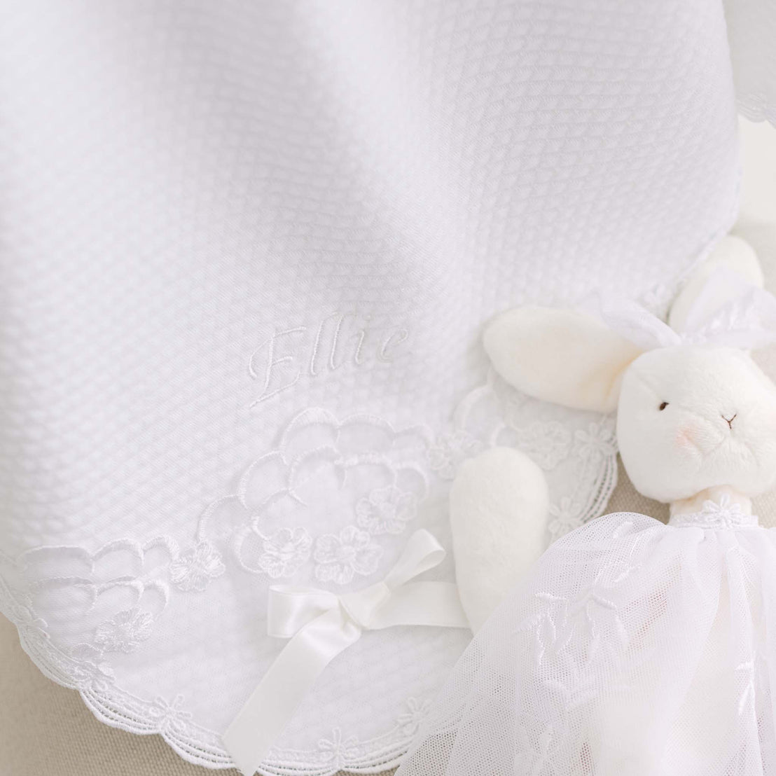 White plush bunny with a quilt blanket on a light background.