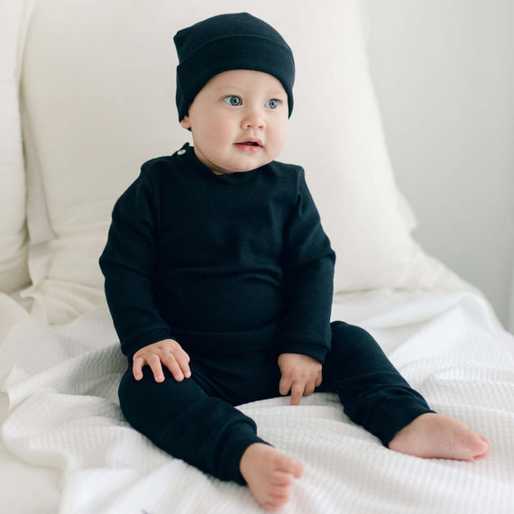 Baby boy sitting on the Elliott Blanket and wearing the navy ribbed cotton top and leggings (and Navy Ribbed Pima Beanie). The top and leggings are made out of 100% ribbed textured cotton with button detail on leggings.