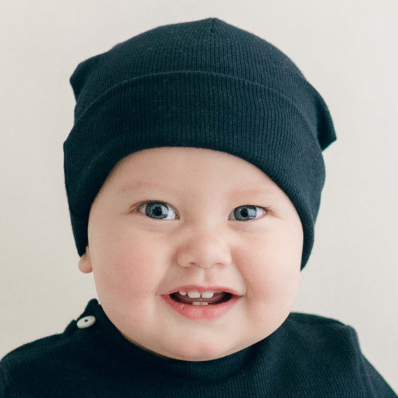 Smiling baby boy wearing the navy Ribbed Pima Beanie made from 100% ribbed textured Pima cotton.