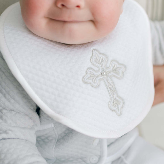 Baby wearing a bib with a cross design