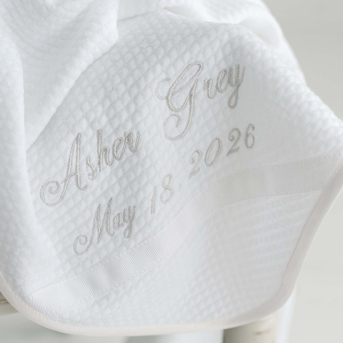 White textured blanket with embroidered text on a light background