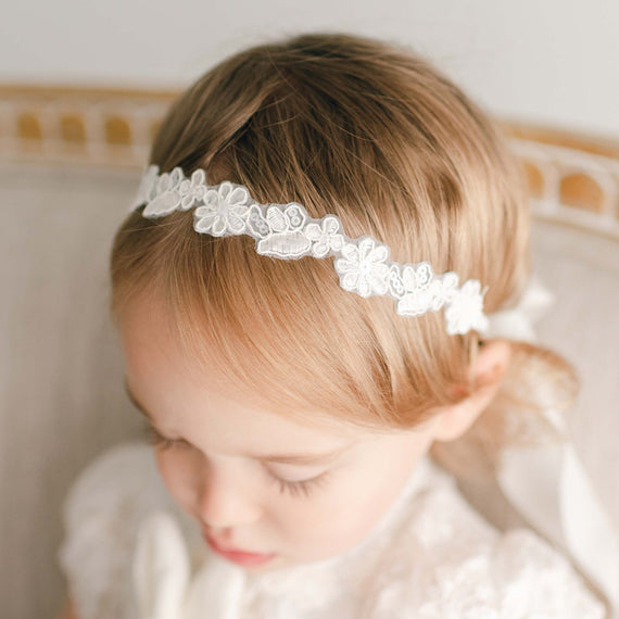 Baby girl wearing lace floral headband - part of the Baby Beau & Belle baptismal collection.