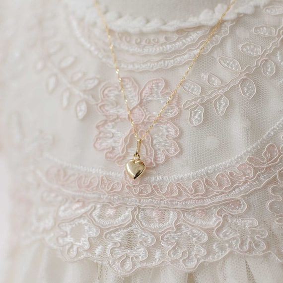 Gold heart-shaped pendant necklace on a lace fabric background