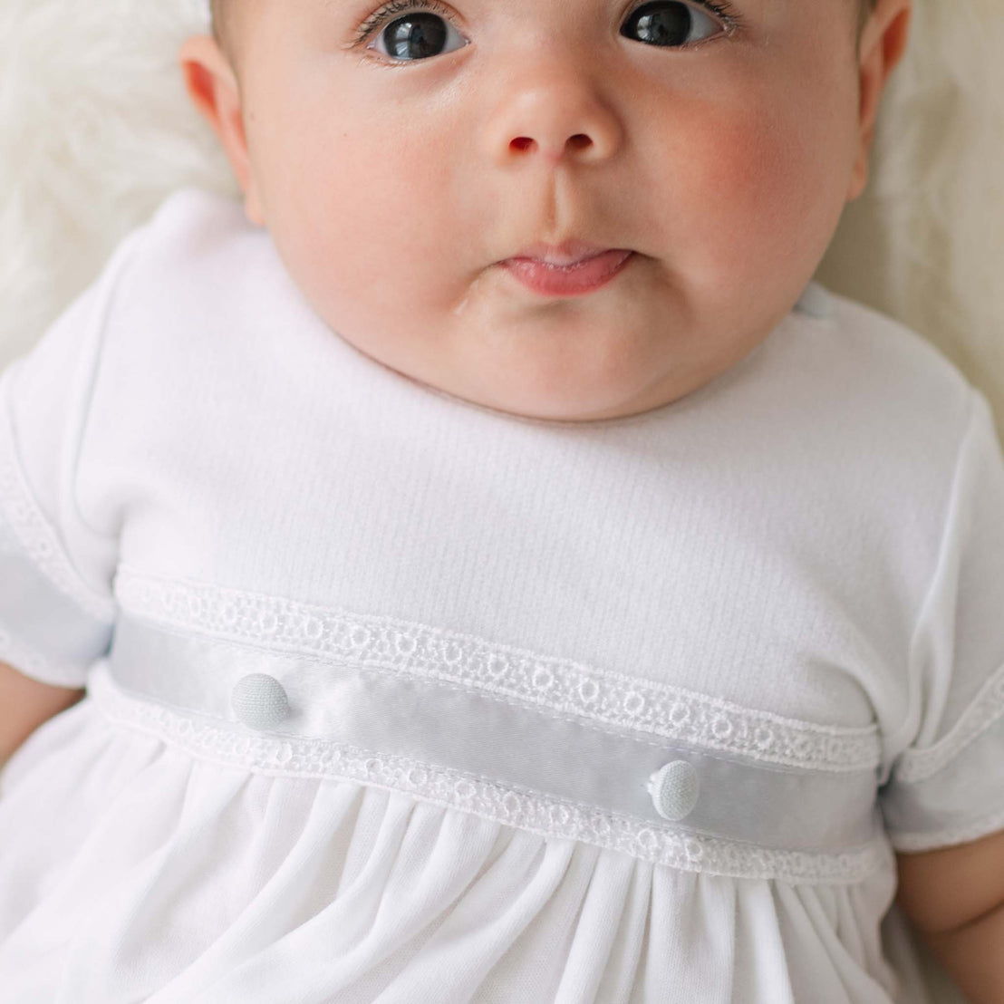 Close-up of a baby wearing a white dress with lace details.