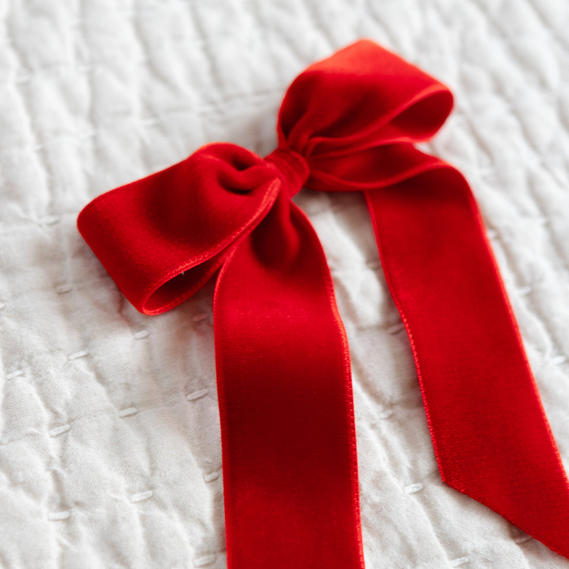 Red velvet bow on a textured white surface.