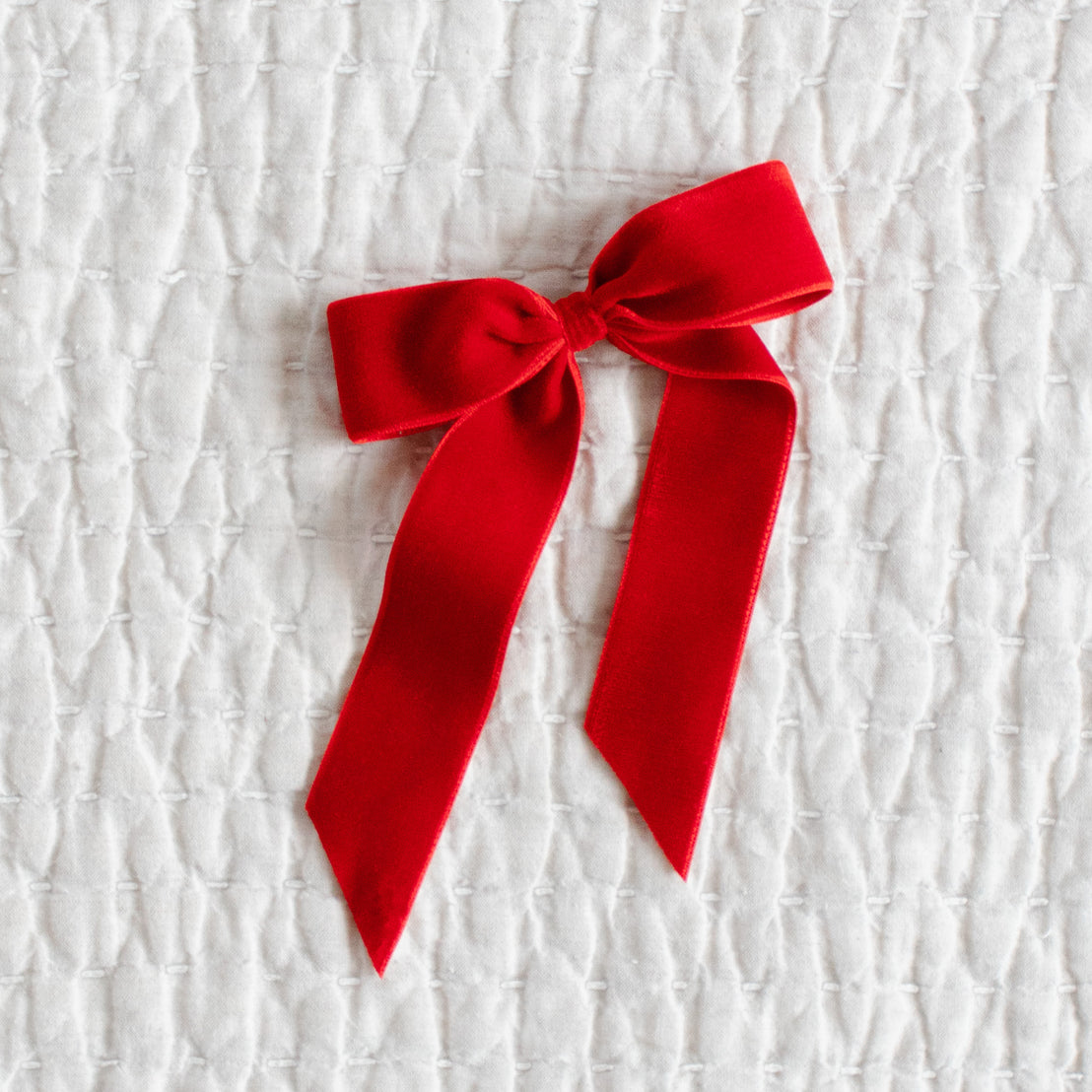 Red velvet bow on a textured white background.