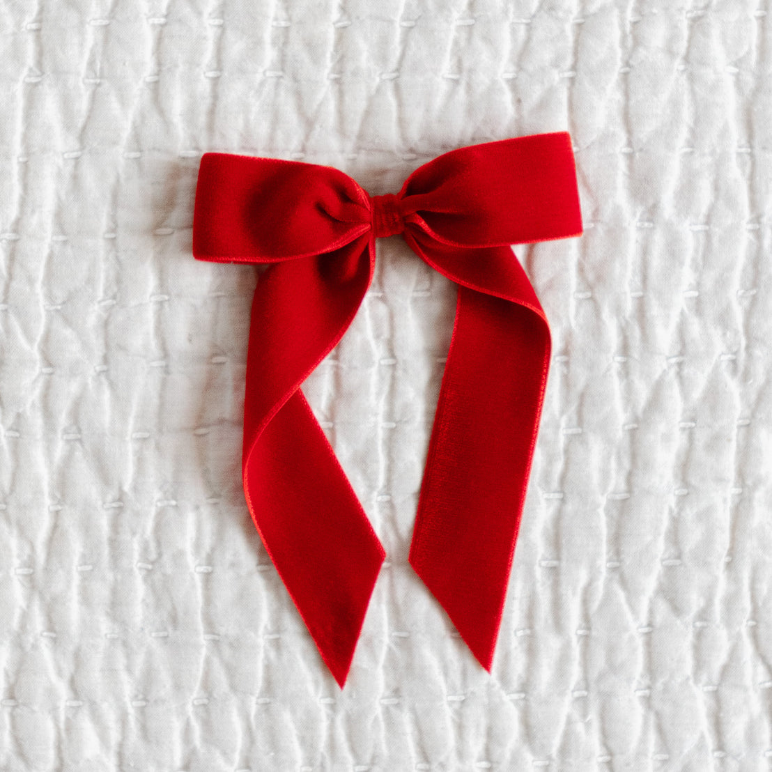 Red velvet bow on a textured white background.