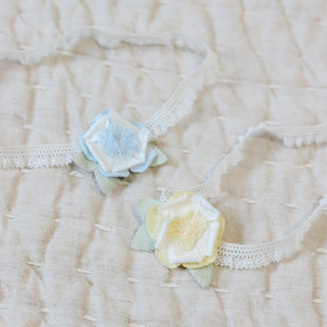 Close up flat lay photo comparison of the yellow and blue Lillian Linen Flower Headband. Details show a linen flower 