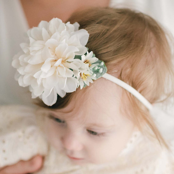 Baby wearing an Ingrid Flower Headband crafted with a super soft hand-stretched nylon band and featuring an ivory dahlia and green leaves