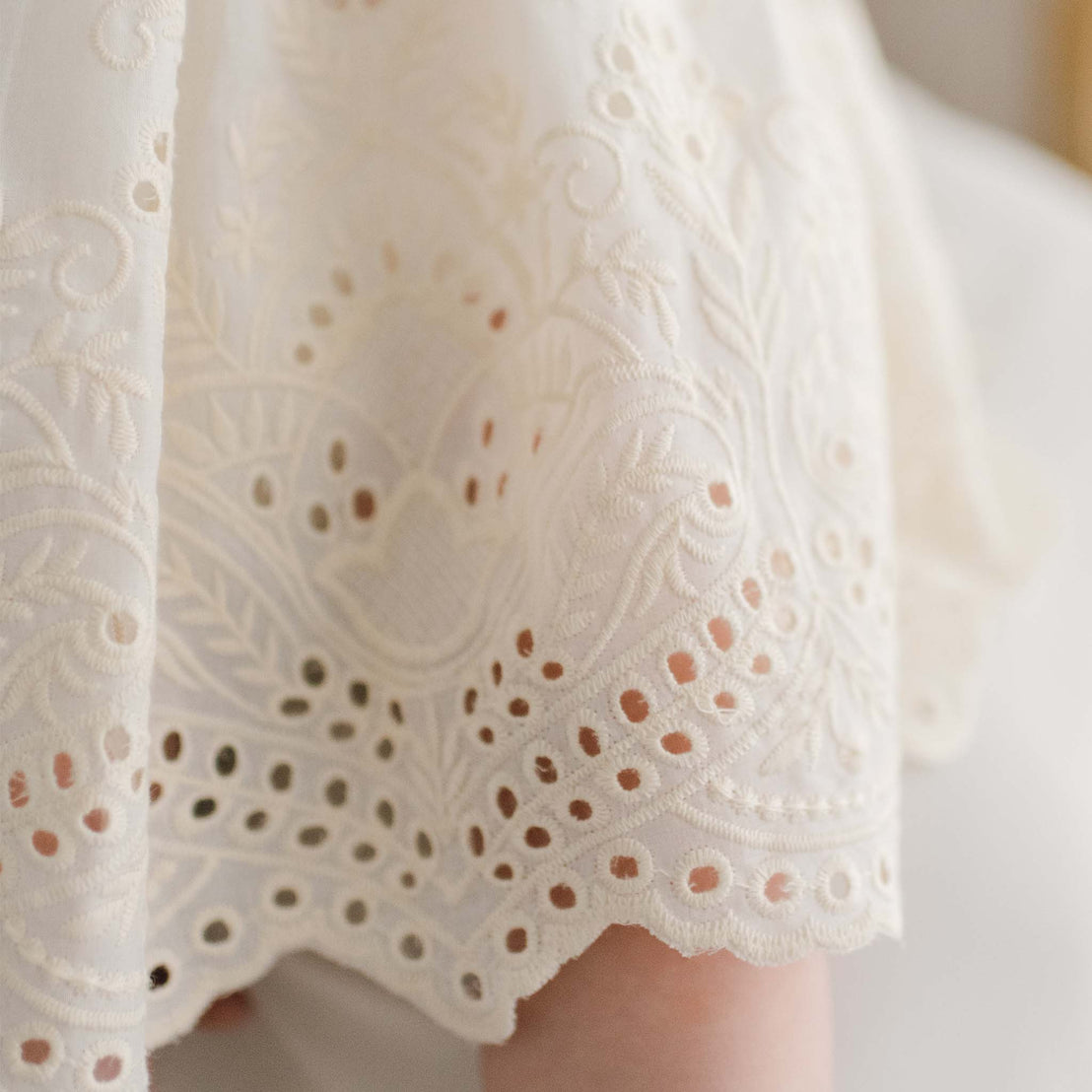 Detail of the ivory Ingrid Romper Dress skirt showcasing the unique design and cotton embroidery